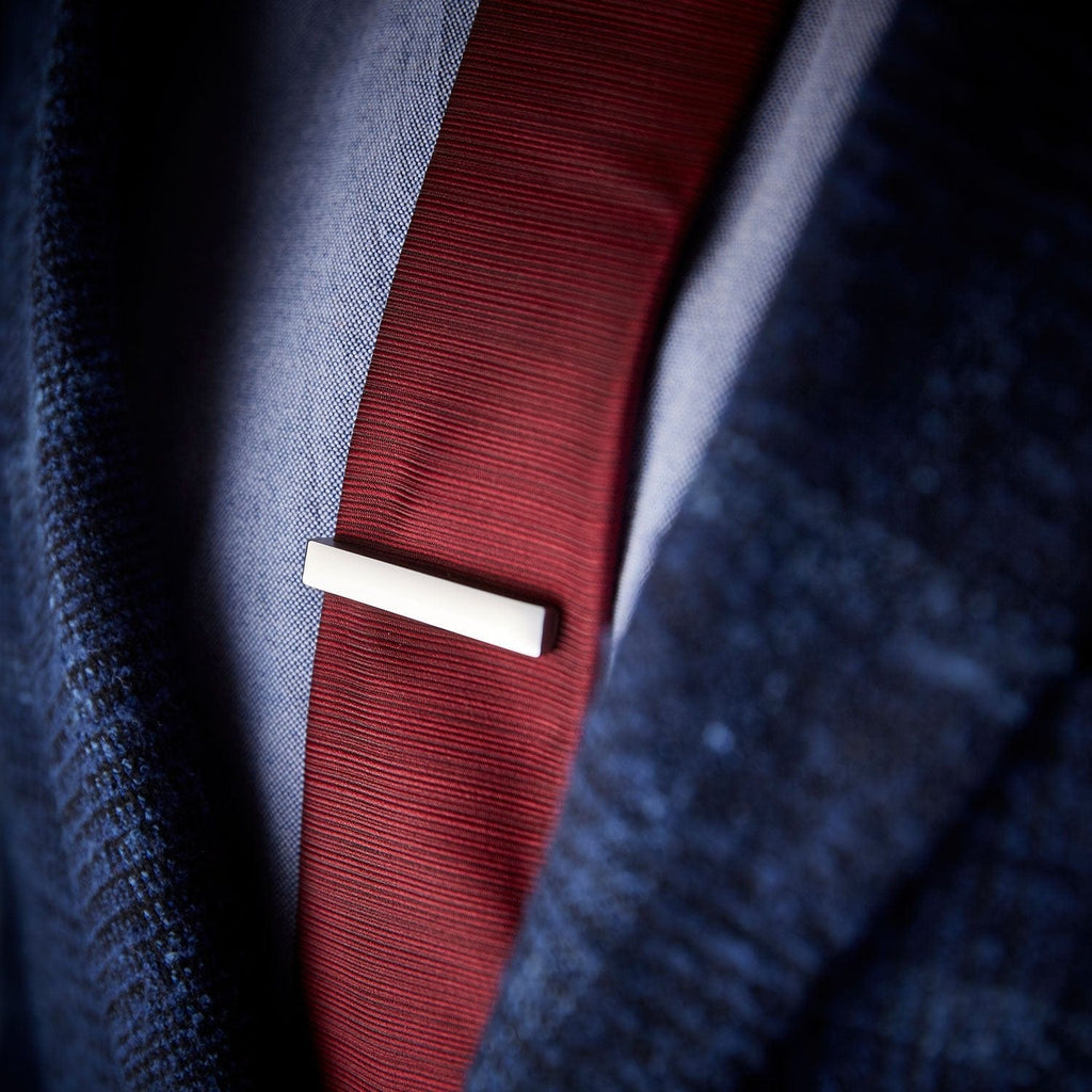Stainless steel tie bar by Man & Bear, modelled with a blue suit and red tie