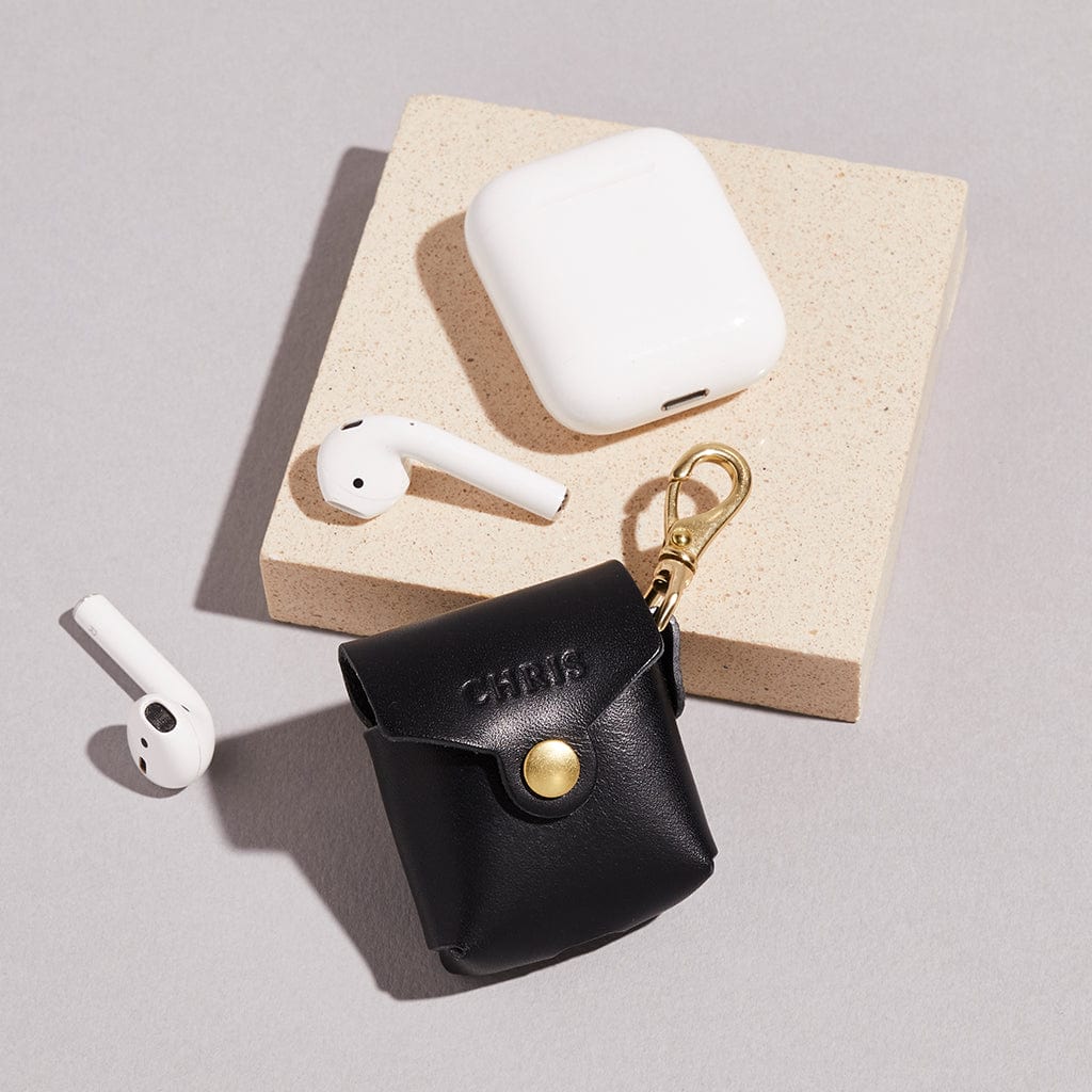 Black leather AirPod case with personalised name, shown with headphones