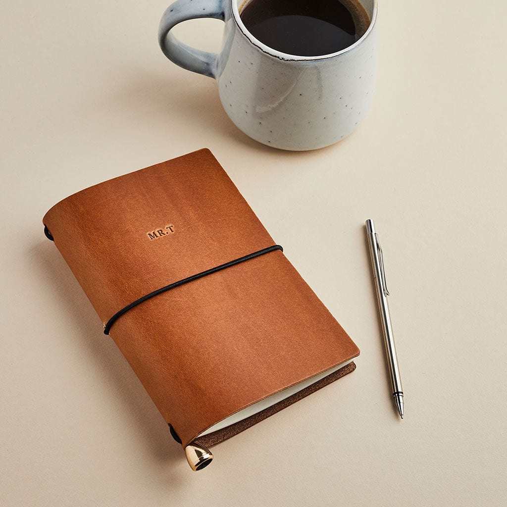 Brown leather notebook with personalised initials - shown on a desk with a mug and pen - made by Man & Bear