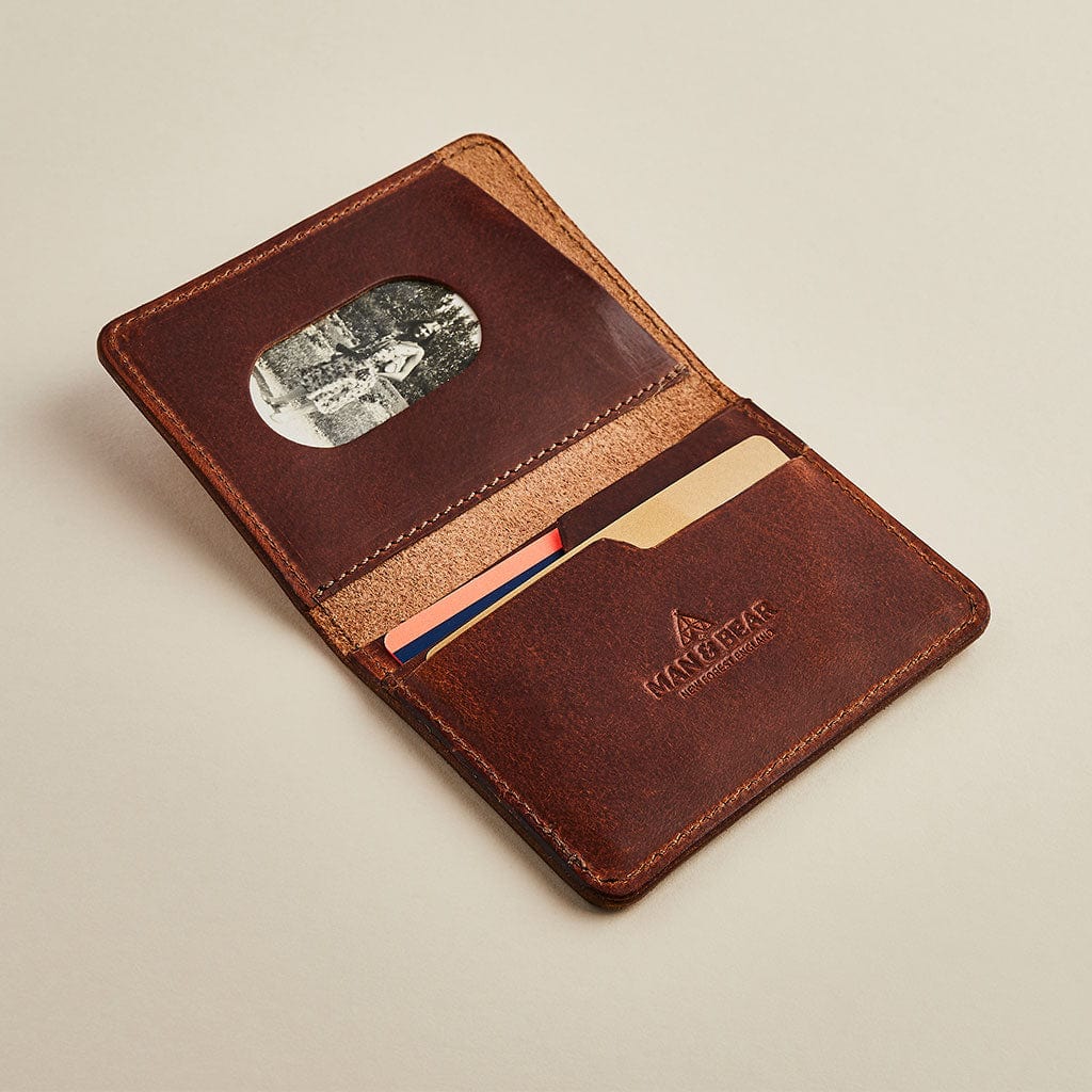 A brown leather men's wallet with card slots, showing the Man & Bear logo