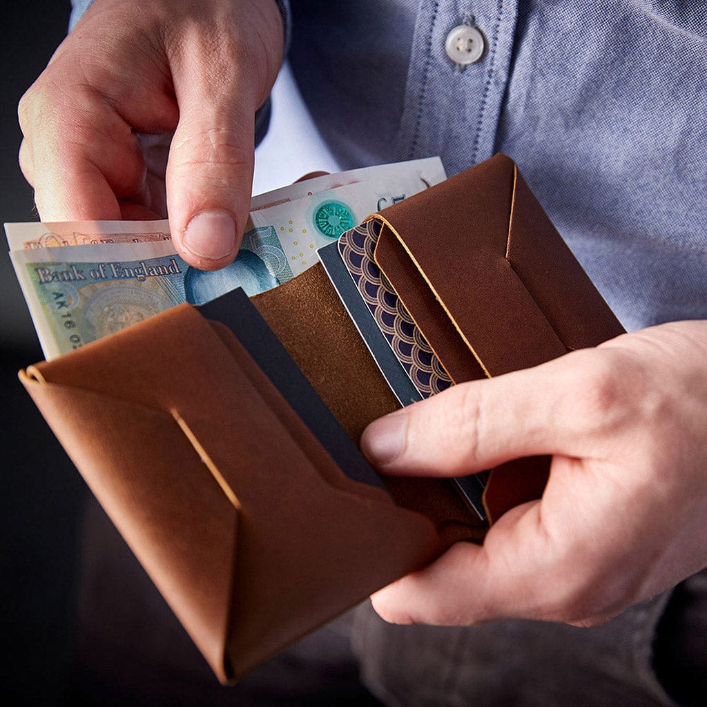 Brown leather origami wallet by Man & Bear, modelled in hand with cards and notes